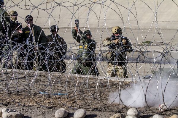 W. Lopez y D. Cody oficiales de la USBP (border patrol) disparan gases lacrimógenos contra la manifestación de centroamericanos en territorio mexicano W. Lopez y D. Cody oficiales de la USBP (border patrol) disparan gases lacrimógenos contra la manifestación de centroamericanos en territorio mexicano - Sputnik Mundo