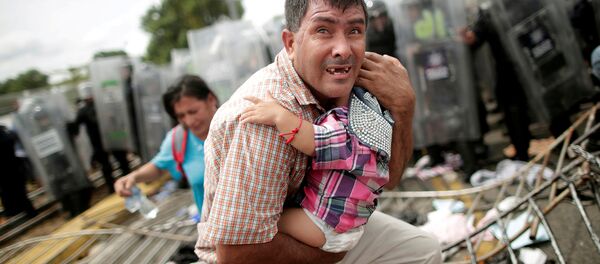 Un migrante trata desesperadamente de proteger a su bebé durante un choque en el cruce de la frontera entre México y Guatemala, el 19 de octubre de 2018 Un migrante trata desesperadamente de proteger a su bebé durante un choque en el cruce de la frontera entre México y Guatemala, el 19 de octubre de 2018 - Sputnik Mundo