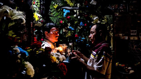 Culiacán, Sinaloa. Hombre reza frente a la imagen de Jesús Malverde en su capilla. - Sputnik Mundo