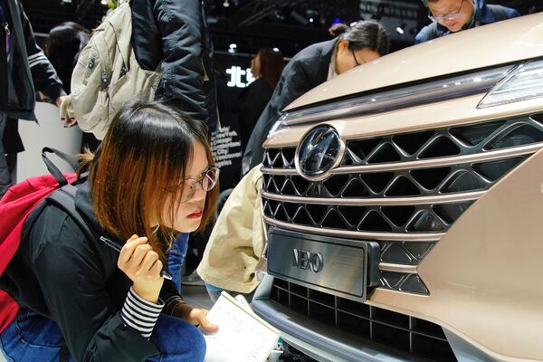 Журналистка смотрит на автомобиль Hyundai Nexo на Шанхайском международном автосалоне - Sputnik Mundo