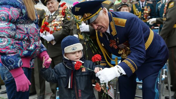 Un niño regala claveles rojos a un veterano durante las celebraciones del Día de la Victoria de 2017, en el Parque de la Victoria en Moscú - Sputnik Mundo