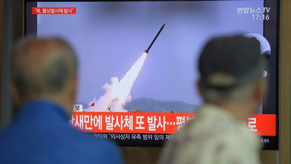 Ciudadanos de Seúl ven un programa de televisión que muestra imágenes de archivo de los proyectiles lanzados por Corea del Norte - Sputnik Mundo