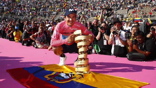 Richard Carapaz ostentando el primer premio del Giro de Italia 2019 sobre la bandera de Ecuador - Sputnik Mundo