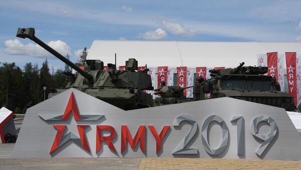 Un tanque y un vehículo militar detrás del logo Army 2019   - Sputnik Mundo