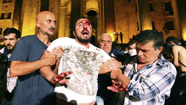 Manifestantes ayudan a un hombre herido durante las protestas en Tiflis - Sputnik Mundo
