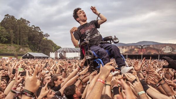 Decenas de jóvenes levantan la silla de ruedas de un muchacho con parálisis cerebral para que pudiera ver un concierto en el festival  Resurrection Fest - Sputnik Mundo