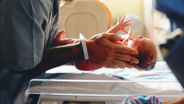 Un doctor sostiene a un bebé recién nacido - Sputnik Mundo