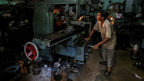 Un trabajador en un torno mientras fabrica piezas de repuesto de cajas de cambios para automóviles en un taller en Calcuta, la India. - Sputnik Mundo