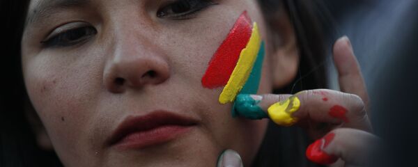 Una mujer pinta los colores de la bandera boliviana en su rostro Una mujer pinta los colores de la bandera boliviana en su rostro - Sputnik Mundo