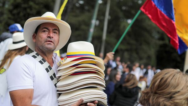 Un hombre lleva los sombreros con las banderas colombianas  - Sputnik Mundo