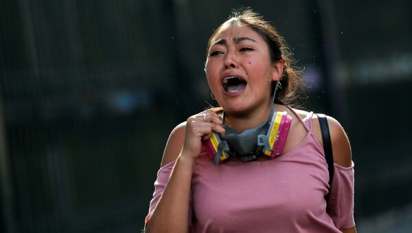 Una mujer chilena corre durante las protestas en Santiago - Sputnik Mundo