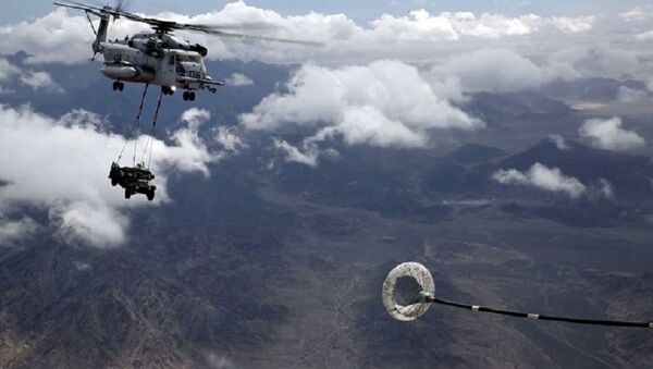 Un helicóptero realiza un repostaje aéreo mientras carga un todoterreno - Sputnik Mundo