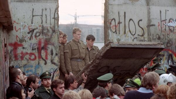 Guardias fronterizos de Alemania Oriental aparecen tras el muro de Berlín después que los manifestantes derribaron un segmento  - Sputnik Mundo