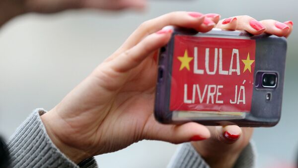 Una mujer sostiene un teléfono celular con un mensaje en apoyo a Lula - Sputnik Mundo