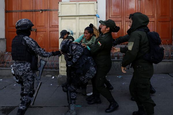 Miembros de las fuerzas de seguridad sostienen a una mujer durante los enfrentamientos entre partidarios del expresidente boliviano, Evo Morales, y las fuerzas de seguridad en La Paz (Bolivia). - Sputnik Mundo
