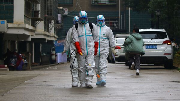 Unos trabajadores del departamento de control y prevención de enfermedades de la provincia china de Jiangxi desinfectan un área residencial después del brote de un nuevo coronavirus - Sputnik Mundo