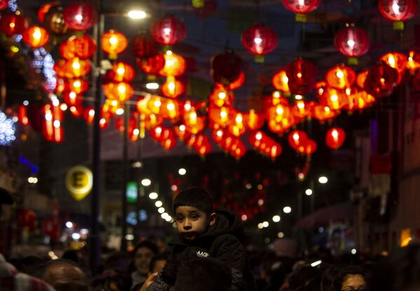 Un niño pasea en los hombros de su padre en el barrio chino durante el festejo del año 4718 en la Ciudad de México. Durante los festejos, los comerciantes del lugar se organizan para decorar y presentar la danza del león que atrae abundancia y salud. - Sputnik Mundo