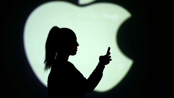 Una mujer con un dispositivo electrónico delante del logo de Apple - Sputnik Mundo