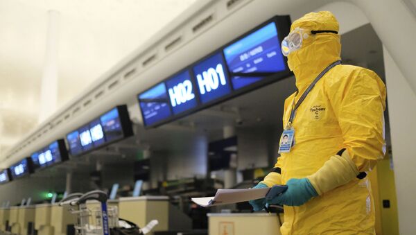 Работник в защитном костюме в аэропорту Уханя - Sputnik Mundo