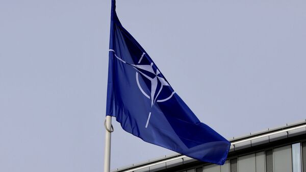 La bandera de la OTAN y de algunos de sus miembros ondean frente a la sede de la organización en Bruselas - Sputnik Mundo