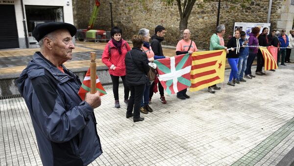 Un señor sostiene un bastón con la bandera vasca al lado de personas que llevan la catalana - Sputnik Mundo