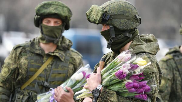 Militares rusos sostienen flores que regalarán con motivo del Día de la Mujer - Sputnik Mundo