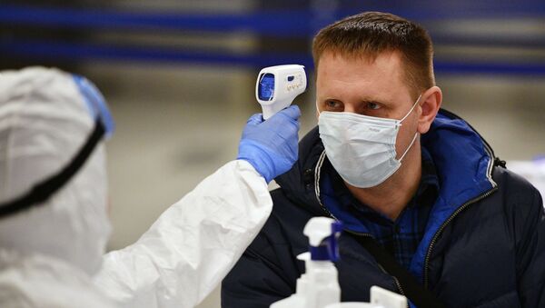 Un médico tomando la temperatura a un hombre con mascarilla durante brote de coronavirus en Moscú, Rusia - Sputnik Mundo