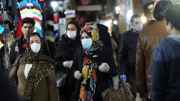 Personas usan mascarillas y guantes protectores mientras caminan en Teherán, Irán - Sputnik Mundo