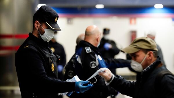 Un policía y un hombre con mascarillas en Madrid durante el brote del coronavirus - Sputnik Mundo