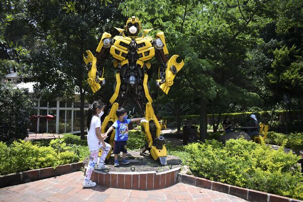 Un niño juega con la estatua del transformer de la película Bumblebee en la Ciudad de Guatemala, ambos llevan máscaras  - Sputnik Mundo