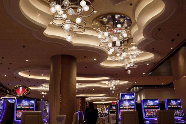 A woman walks past some slot machines at MGM Cotai Resort in Macau - Sputnik Mundo