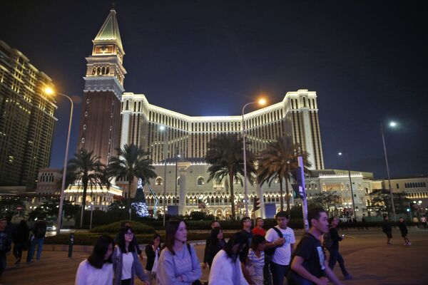 People walk across a road in front of the Venetian Macao casino resorts in Macau - Sputnik Mundo