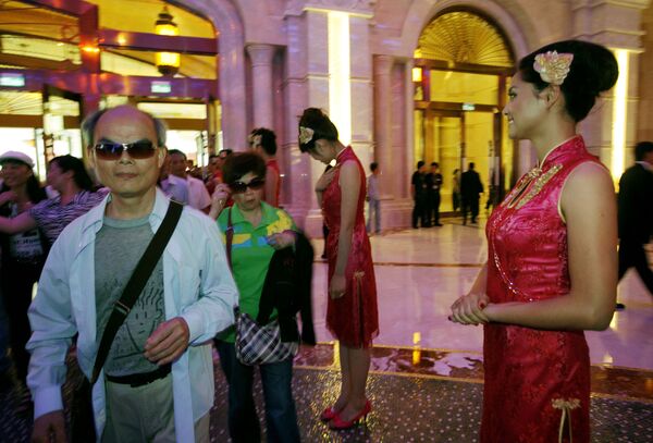 Mainland Chinese visitors walk past attendants at the Galaxy Macau in Macau.  - Sputnik Mundo