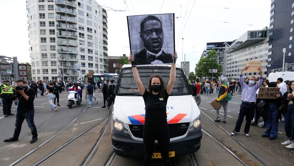 Una manifestante con el retrato de George Floyd en las protestas antirascistas en EEUU - Sputnik Mundo