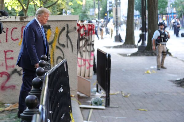Президент США Дональд Трамп проходит мимо здания, исписанного граффити протестующими в парке Лафайет, напротив Белого дома - Sputnik Mundo