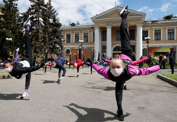 Учащиеся школы художественной гимнастики в защитных масках и перчатках принимают участие в тренировке на открытом воздухе, чтобы привлечь внимание к закрытию учебного центра в Киеве, Украина - Sputnik Mundo