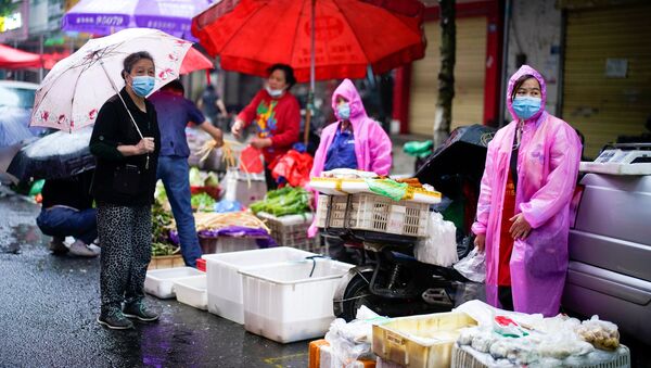 Vendedores de un mercado en Wuhan visten equipos de protección durante la crisis por COVID-19 - Sputnik Mundo