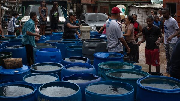 La gente llena los envases plásticos con agua en Petare, Caracas - Sputnik Mundo