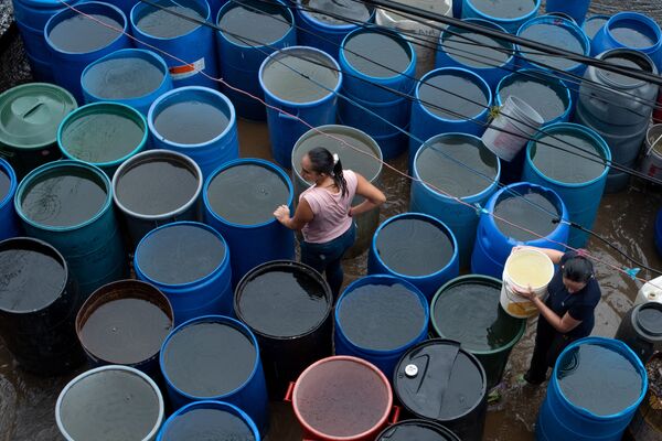 La gente llena los envases plásticos con agua en Petare, Caracas - Sputnik Mundo