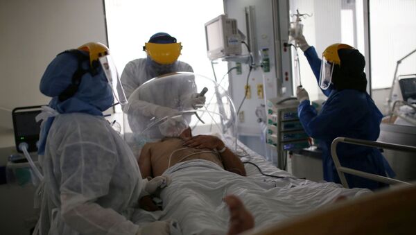 Los médicos atienden a un paciente con coronavirus en Bogotá - Sputnik Mundo