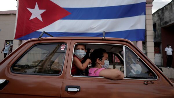 Dos persona el un coche y una bandera de Cuba - Sputnik Mundo
