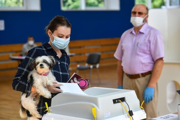 Девушка с собачкой голосует по вопросу одобрения изменений в Конституцию России на избирательном участке в Москве - Sputnik Mundo