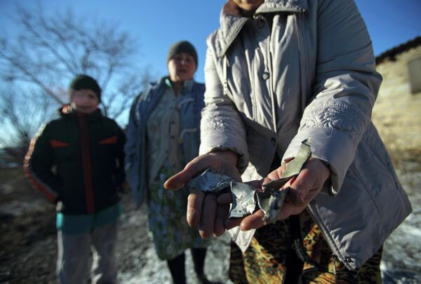 Una mujer muestra fragmentos de metralla procedentes de un ataque de artillería contra Donetsk - Sputnik Mundo